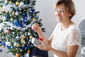 Mature woman opening a present in front of the Christmas tree