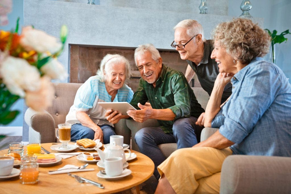 Smiling seniors sharing a tablet computer while enjoying breakfast