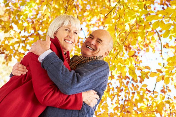 Fashion Senior Couple Hugging Underneath Autumn Tree Loving Embracing Smiling Outdoors Caption