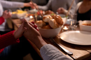 Family holding hands around the dinner table