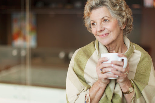Elderly lady holding mug smiling