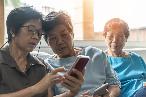 Three senior asian sisters reading on a cell phone
