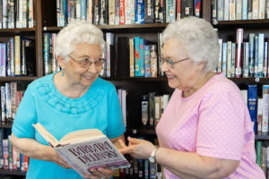 Two sisters reading a book in the Terrace Retirement library