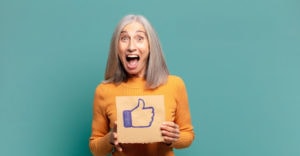A happy senior holding a Facebook thumbs up