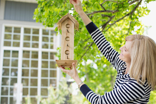 A lady hanging up a bird feeder
