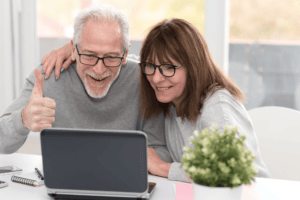 Senior parents smiling and giving thumbs up at laptop