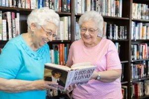 Two senior women enjoying conversation over a large print book